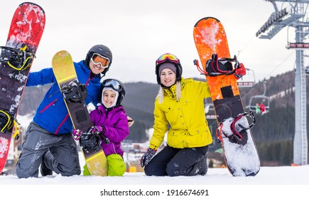 Family Of Snowboarders At Winter Resort In The Mountains