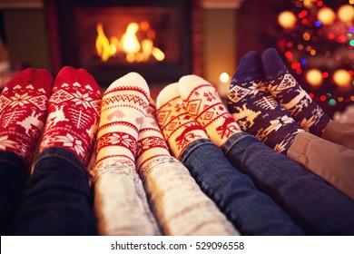 Family In Socks Near Fireplace In Winter On Christmas Time
