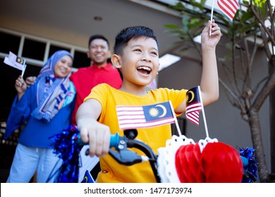 Family And Son Celebrating Malaysia Merdeka Or Malaysian Independence Day By Decorating Bicycle At Home Together