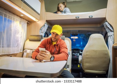 Family Spending Time Inside Camper Van RV Motorhome With Their Smartphones. Internet Connection While RVing Concept Photo. Campsite WiFi Signal.