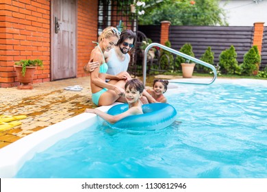 Family Spending Time Near Swimming Pool At Countryside Backyard On Summer Day