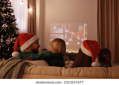Family spending time together near video projector in room, back view. Christmas atmosphere - Powered by Shutterstock