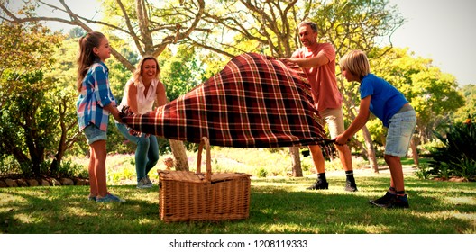 Family spreading the picnic blanket in park - Powered by Shutterstock