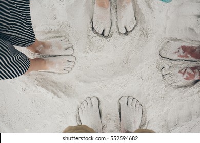 Family Standing Barefoot On White Sand Beach In New Zealand