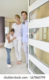 Family Standing At Front Door To Invite People In