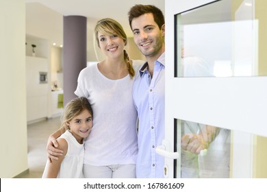 Family Standing At Front Door To Invite People In