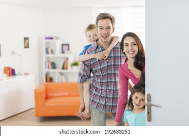 Family Standing At Front Door To Invite People At Home