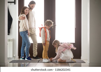 Family standing in hallway and gather to school or for a walk. Husband and wife embrace and look at their pretty children. Eldest daughter helps little brother put his shoes. Care and support concept - Powered by Shutterstock