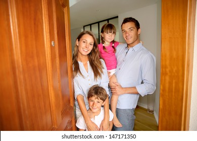 Family Standing On The Entrance Door Of New Home