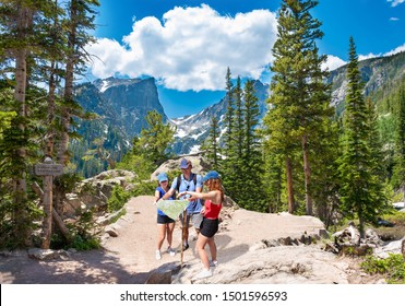 Family Standing On The Hiking Trail Looking At Map. Smiling People Enjoying Time Together In The Mountains On  Emerald Trail. Estes Park, Rocky Mountains National Park, Colorado, USA.