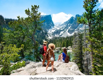 Family standing on top of the mountain enjoying  beautiful scenery. Early summer landscape with lake  and snow covered mountains.  Dream Lake, Rocky Mountains National Park, Colorado, USA.