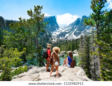 Family standing on top of the mountain enjoying  beautiful scenery. Early summer landscape with lake  and snow covered mountains.  Dream Lake, Rocky Mountains National Park, Colorado, USA.