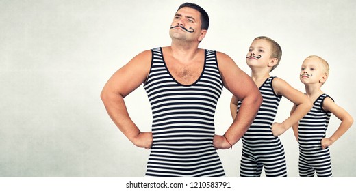  Family Of Strongman. The Father Of Two Sons In Vintage Costume Of Athletes Perform Strength Exercises. Family Look.