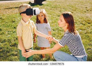 Family In A Summer Park. Mother With Children. Cute Little Boy Un A Vr Glasses