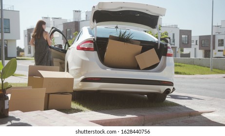 Family Summer Roadtrip To The Seaside. Two Cute Siblings Sister And Brother Loading A Heavy Suitcase In Trunk Standing Near The Car In The Courtyard.