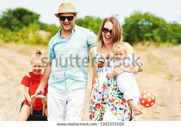 Family, summer vacation, adoption and people\
concept - happy man, woman and daughters in sunglasses, with\
suitcases  having fun over blue sky background\
