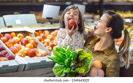 Family In The Supermarket. Beautiful Young Mom And Her Little Daughter Smiling And Buying Food. The Concept Of Healthy Eating. Harvest