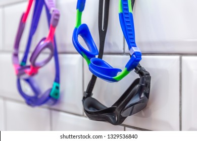 Family Of Swimming Goggles Hanging On A Tiled Wall