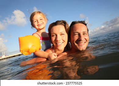 Family Swimming In Sea At Sunset