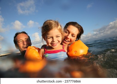Family swimming in sea at sunset