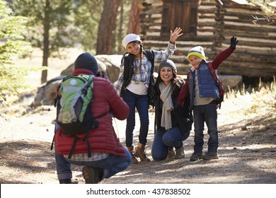 Family Taking A Photo In Front Of A Log Cabin, Close Up