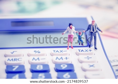 Family tax benefit or FTB, child care fee concept : Couple holds a child on a calculator, depicting a social security payment which is distributed to the parents or guardians of children or teenagers.