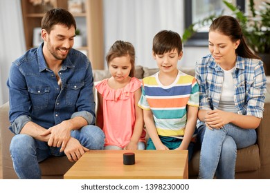 Family, Technology And Internet Of Things Concept - Happy Father, Mother, Little Son And Daughter With Smart Speaker At Home