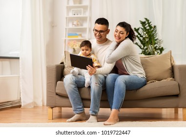 family, technology, parenthood and people concept - happy mother and father showing tablet pc computer to baby daughter at home - Powered by Shutterstock