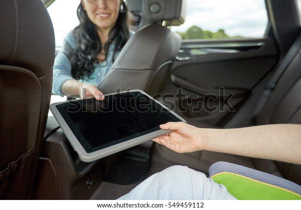 family,\
technology, road trip, travel and people concept - happy woman\
giving tablet pc computer to her child in\
car