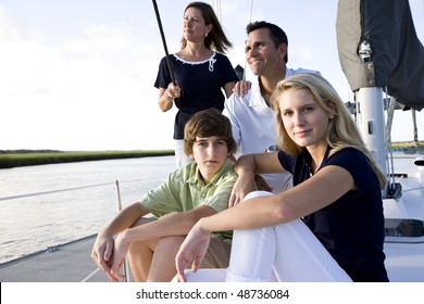 Family With Teenage Children Sitting On Boat At Dock On Sunny Day