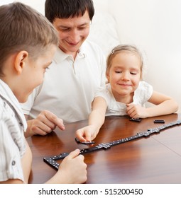 Family That Plays Dominoes. Father Playing With Children At Home