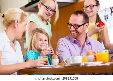 Family In Their Home Having Breakfast With Eggs, Fruit, Coffee And Juice 