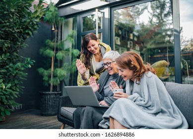 Family Of Three Beautiful Women Having Video Call On Laptop In The Home Garden.