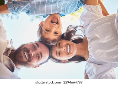 Family of three from below. Portrait of a young couple and their cute son posing outside with the clear blue sky in the background. Happy boy smiling with his mother and father outdoors during summer - Powered by Shutterstock