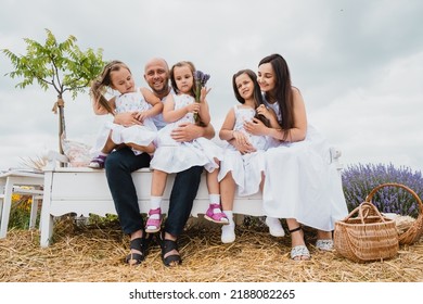 Family with three children sitting on the bench outdoors in a park talking chatting.Happy Mom, and three children are playing, hugging.cheerful family resting in nature.