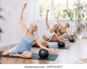 Family of three generations doing soft ball pilates exercises during group pilates class in fitness studio - Powered by Shutterstock