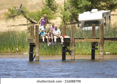 Family Of Three Generations Fishing From Jetty, Motor Home In Background, Low Angle View