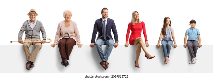 A family of three generations sitting on a blank panel and smiling at camera isolated on white background