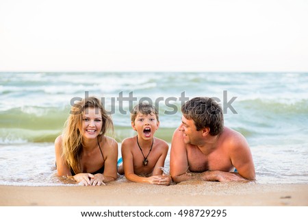 Family of three having fun at the beach, smiling and playing together