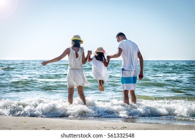 Familia de tres personas que se divierten en la playa tropical