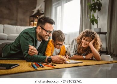 Family of three lie down on the carpet and draw at home together - Powered by Shutterstock