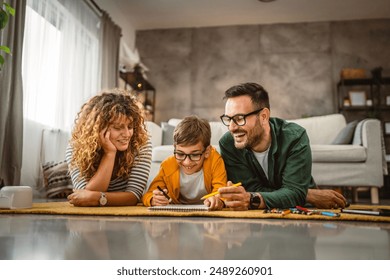 Family of three lie down on the carpet and draw at home together - Powered by Shutterstock