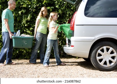 Family Of Three Loading Recycling Into Car, Side View