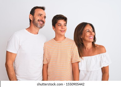 Family Of Three, Mother, Father And Son Standing Over White Isolated Background Looking Away To Side With Smile On Face, Natural Expression. Laughing Confident.