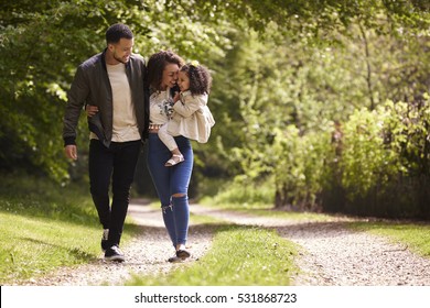 Family of three on a walk, mother holding child, front view