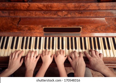 Family Of Three People Is Playing The Piano, Front View. Point Of View Shot