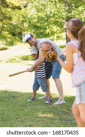 Family Of Three Playing Baseball In The Park