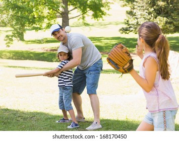 Family Of Three Playing Baseball In The Park