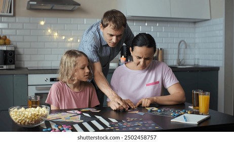 Family of three playing board games at a table in their kitchen, connecting the geometric shapes of a tangram puzzle. Family lifestyle concept - Powered by Shutterstock