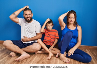 Family Of Three Sitting On The Floor At Home Confuse And Wonder About Question. Uncertain With Doubt, Thinking With Hand On Head. Pensive Concept. 